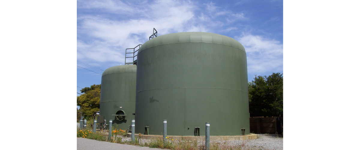 Image shows two large, green water tanks.