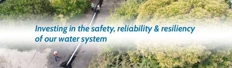 Marin Water staff lay new underground pipeline in roadway. Text reads "Investing in the safety, reliability & resiliency of our water system."