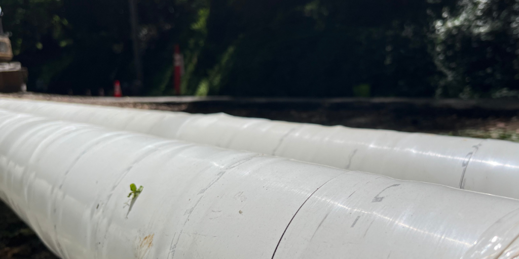 Two pipes sit alongside a roadway.