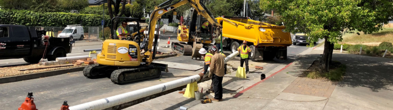 Construction crews work to install a water pipeline along a residential street.