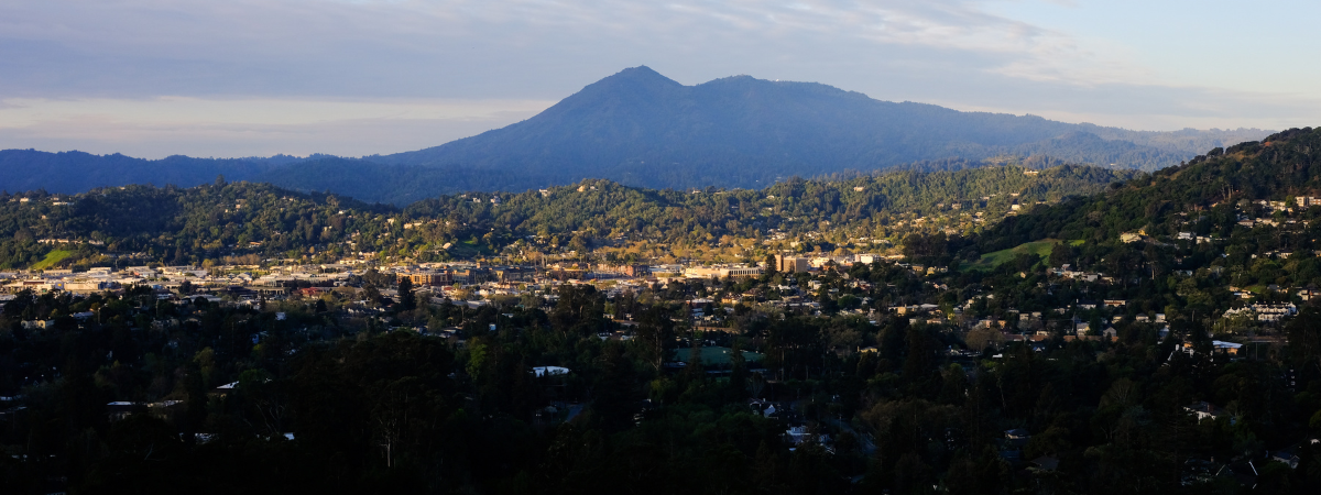 Image shows a community in the foreground, with a mountain in the background.