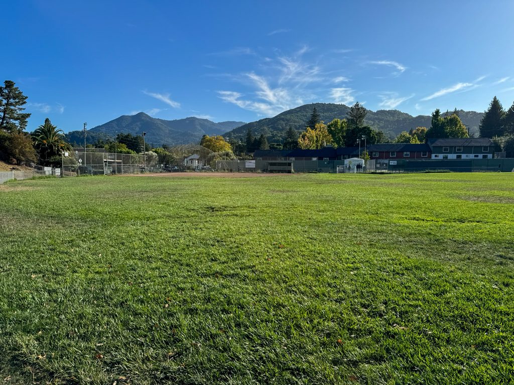 Image shows a baseball field with mountains rising in the background.