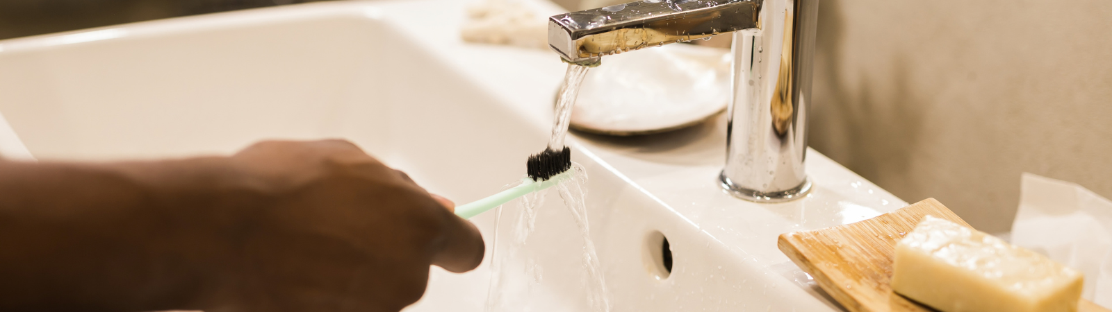 A person rinses a toothbrush in a sink.
